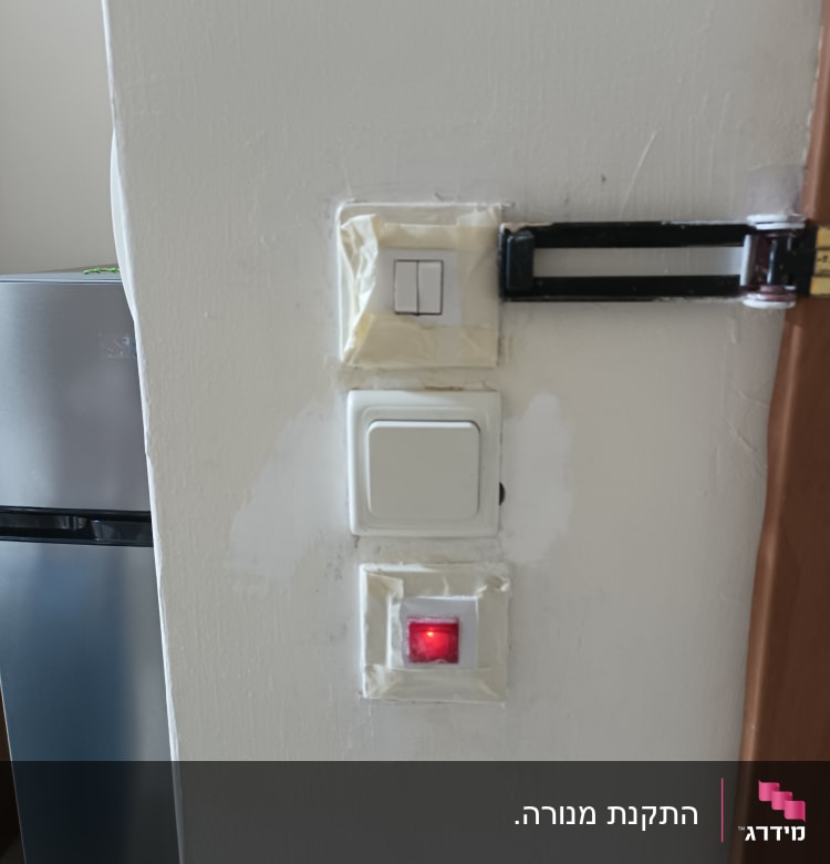 מתגי חשמל על קיר עם נורית אדומה דולקת